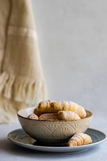 A decorative bowl filled with freshly baked homemade pastries, placed on a plate. The pastries are