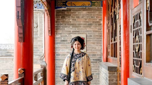 Woman dressed in traditional Qing dynasty clothing stands in Pingyao, China, looking at the camera.