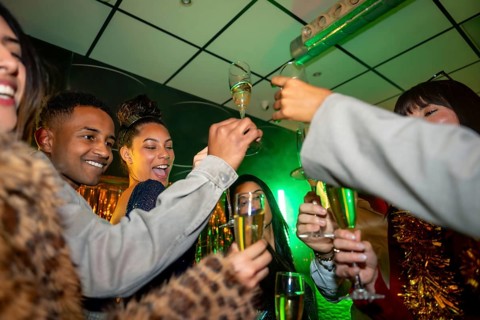 Group of happy multiracial friends enjoying a lively party in a nightclub, smiling and toasting