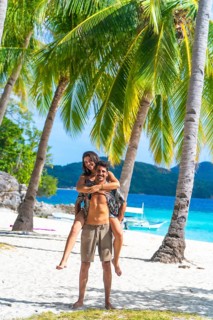 Tourists having fun on a beautiful white sand beach with turquoise water and palm trees on