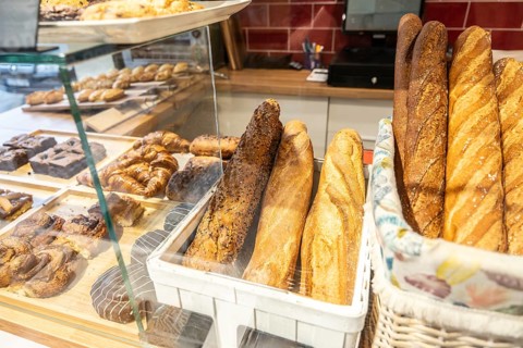 Bakery display case of freshly baked baguettes, croissants and assorted pastries neatly arranged in