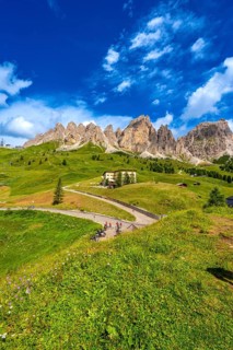 Bikers taking a break at gardena pass admiring the stunning view of the dolomites on a sunny summer