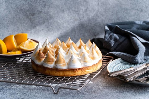 A beautifully homemade lemon cake on a cooling rack, accompanied by fresh lemon slices and vintage