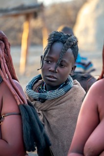 Himba girl, between Himba woman, portrait, in the morning, traditional Himba village, Kaokoveld,
