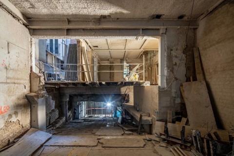 A construction site depicting an interior under renovation. Exposed beams, scaffolding, and