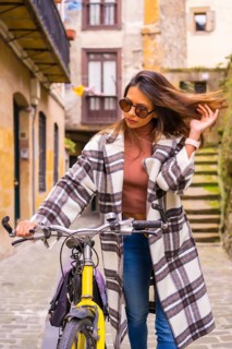 Pretty latin woman with sunglasses doing bicycle sightseeing in the city through the old town.