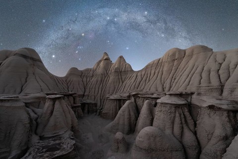 A serene night sky filled with stars illuminates the rugged, textured rock formations at a Utah,