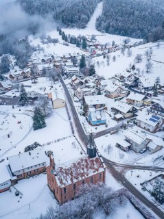 Snowy town view with church, surrounded by wooded hills, Enzklösterle, district of Calw, Black