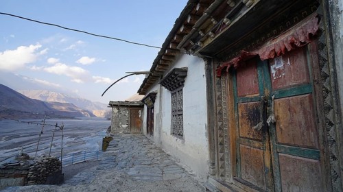 Traditional colorful wooden doors and stone walls with mountain views at dusk, trekking at