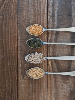 Various healthy seeds filling spoons on a rustic wooden background