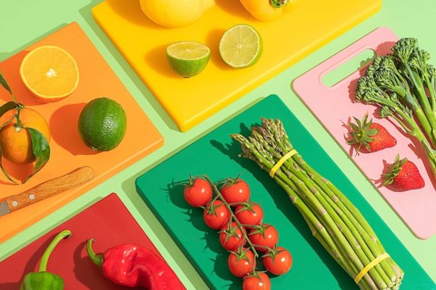 A vibrant display of fruits and vegetables on colorful cutting boards, featuring oranges, tomatoes,