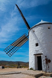 White windmill with a metal device of Don Quixote in front, under a clear sky, rural environment,