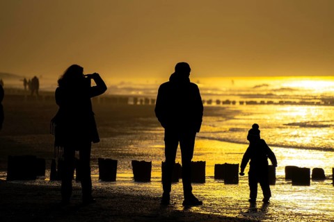 Winter on the North Sea, sunset at sea, beach walkers, coastal protection, through wooden posts,