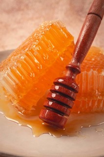 Honeycomb, with a wooden spoon-spindle, on a plate, no people