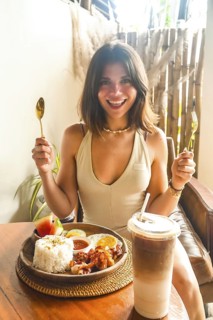 Young woman holding cutlery and smiling, ready to enjoy traditional filipino breakfast with iced