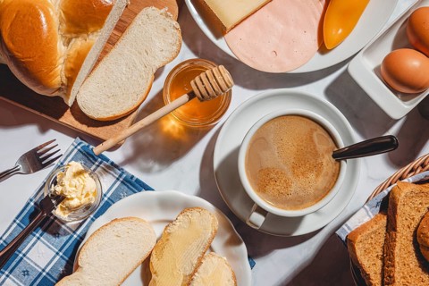 Breakfast, stollen with butter and honey, surrounded by cheese, ham, coffee, peppers and eggs