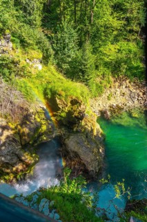 Stunning rainbow forming over waterfall cascading into turquoise water in vintgar gorge near bled,