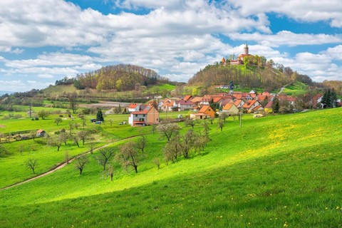 View of hilly landscape with the village of Seitenroda and Leuchtenburg in spring, in front a green