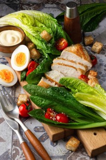 A vibrant image showing fresh Caesar salad ingredients, including romaine lettuce, grilled chicken,