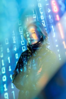 An elderly Asian woman stands confidently in the metaverse, surrounded by virtual elements and