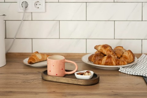 Freshly baked homemade croissants served on a wooden table with a cozy pink mug and a small bowl of