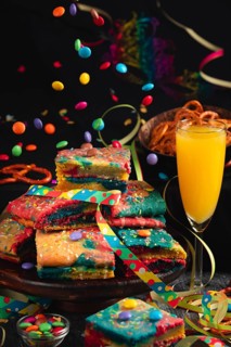 Colourful pieces of cake with sparkling wine and flying chocolate drops in a lively party