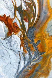 Intricate fractal patterns of vibrant mud textures create a stunning visual captured from above.