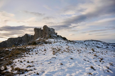 Stunning panoramic view of Montcabrer, Spain, showcasing a snow-covered mountain landscape at dusk,