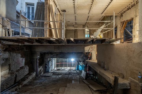 A construction site inside a partially renovated building features an exposed concrete structure,