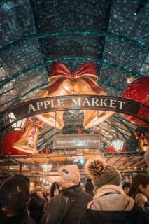 Visitors to Apple Market surrounded by Christmas bells and a sign with handmade art & design,