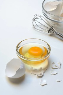 Egg whites and egg yolks in glass bowl and egg shells, whisk