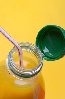 Orange juice in plastic bottle with cap and straw