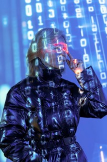 An elderly Asian woman engages with the metaverse, wearing futuristic glasses. Digital numbers