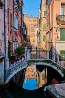View from a gondola on a waterway in Venice going through the houses on a quiet and sunny morning