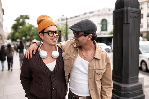 A joyful colombian gay couple enjoying a casual city walk. Both are wearing sunglasses and