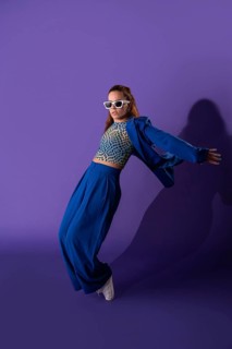 A young woman exudes grace and energy as she performs a dynamic dance against a striking purple