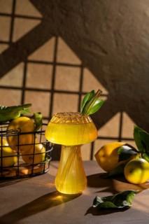 A refreshing lemon drink served in an artistic glass, adorned with green leaves and surrounded by