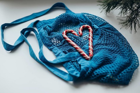 A striking image showcasing heart-shaped candy canes nestled within a vibrant blue string bag,