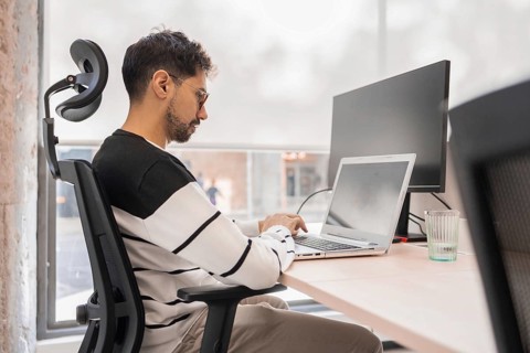 A professional concentrates on his laptop in a modern office environment Natural light illuminates