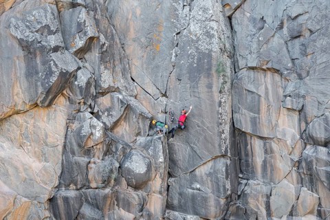 Climbers scale a rugged cliff using traditional techniques, highlighting skill, adventure, and a