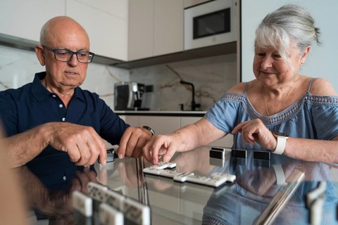 A family gathers in the kitchen, engaging in a lively game of dominoes. The room is filled with