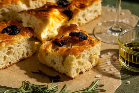 Golden homemade focaccia topped with sun dried tomato and rosemary. Served with olive oil, this