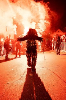 Impressive picture of a costumed participant during a nocturnal street party with glowing fire,