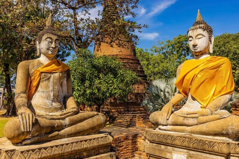 Stone Buddha statues decorated with yellow cloths, historic Buddhist temple complex, Ayutthaya,