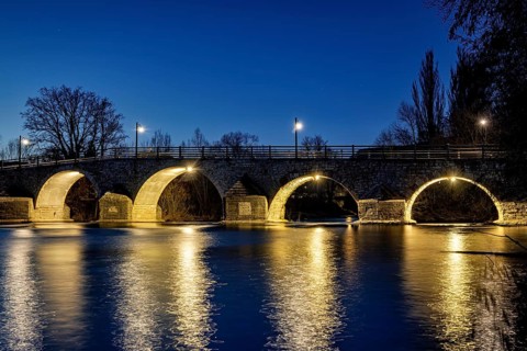 Night view of an illuminated bridge with lights reflecting in the quiet river, The Burgau Bridge in