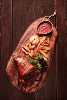 Pork knuckle, in soy-honey sauce, with fried potatoes, on a wooden chopping board, homemade, no