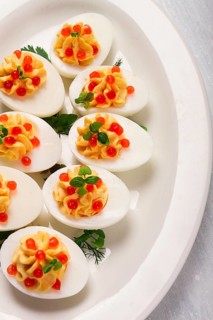 Stuffed eggs, with red caviar, micro greenery, Snack, on a white plate, top view, close-up, no