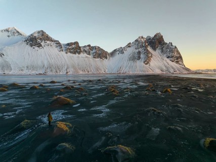 A stunning winter view of Stokksnes Beach in Iceland, featuring rugged snow-capped peaks against a