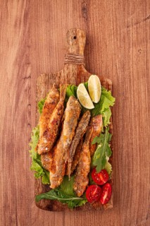 Fried crispy red mullet fish, on a wooden chopping board, with lime, no people