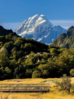 Stunning autumn landscape of Mount Cook, New Zealand, featuring snow capped peaks and lush foliage.